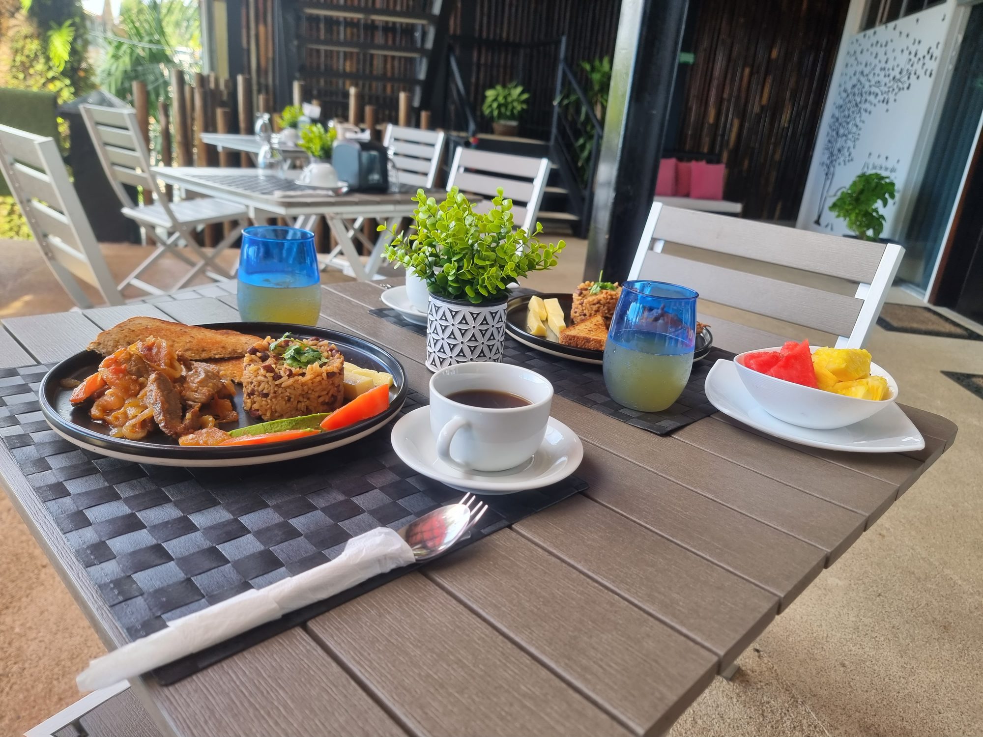Two breakfast plates, coffee, juice, and fresh fruit on the Vista Bistro patio