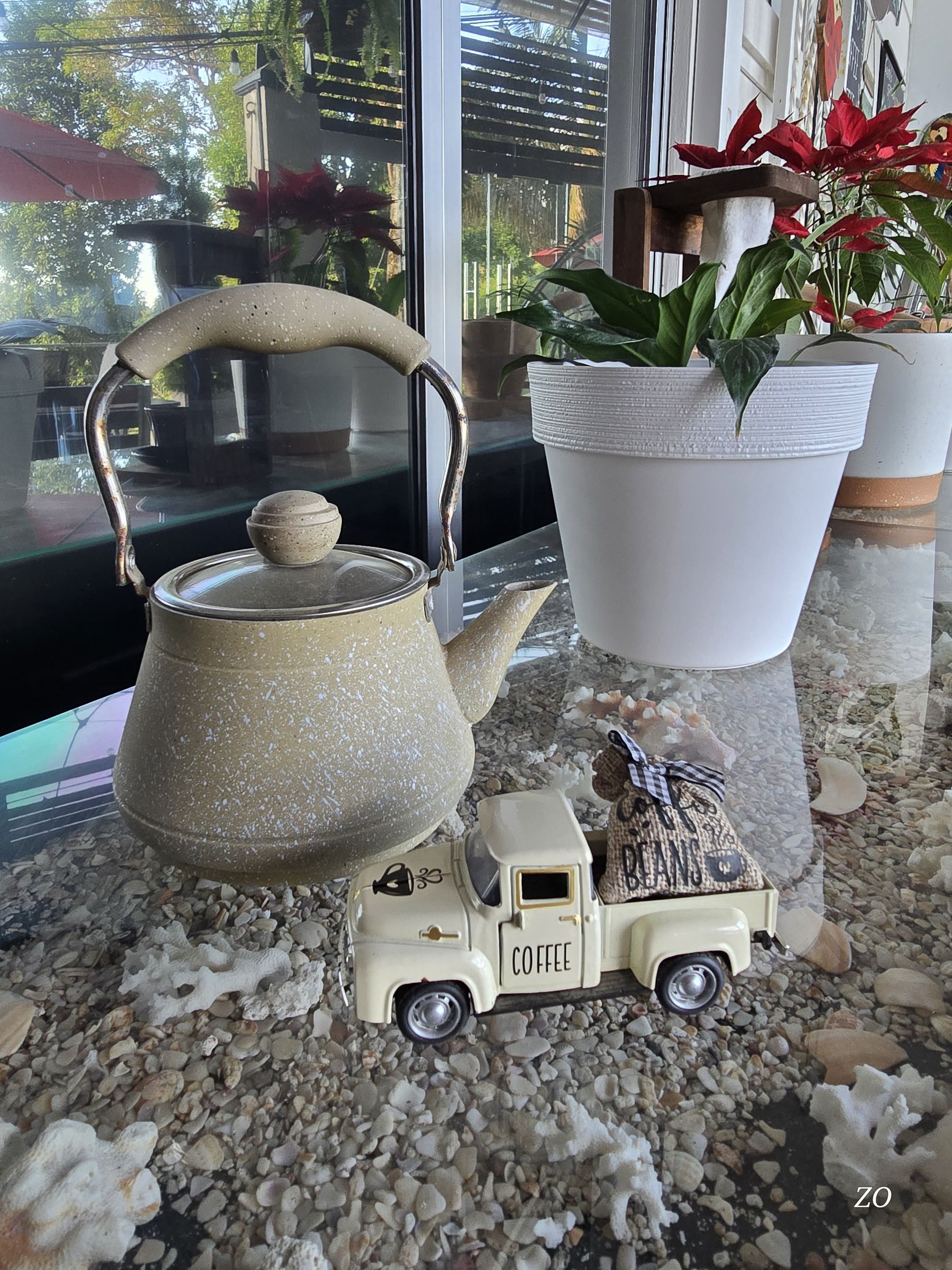 A speckled kettle and a small coffee truck on the counter by the window