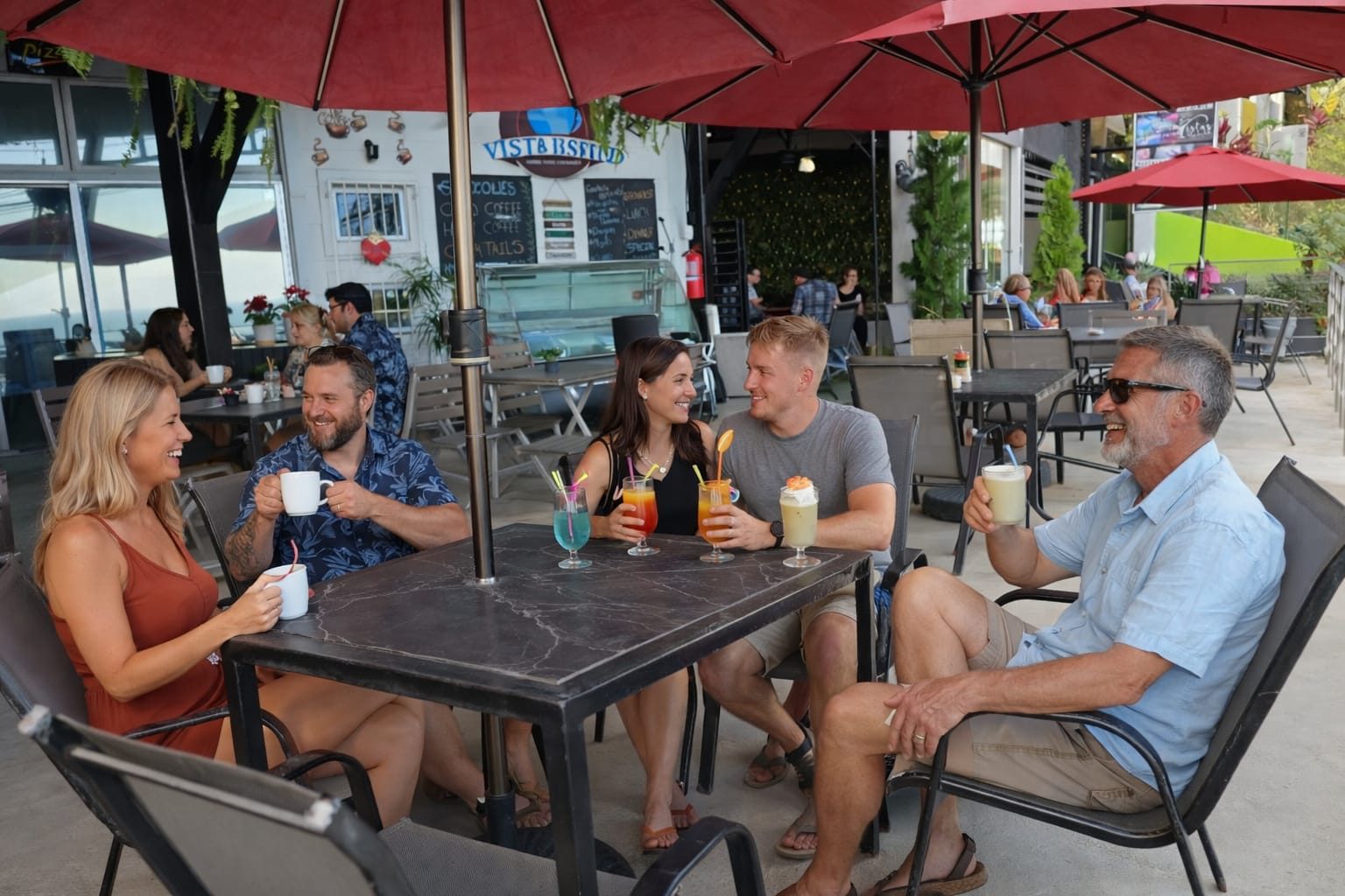 Guests with coffee and cocktails under the red umbrellas at Vista Bistro